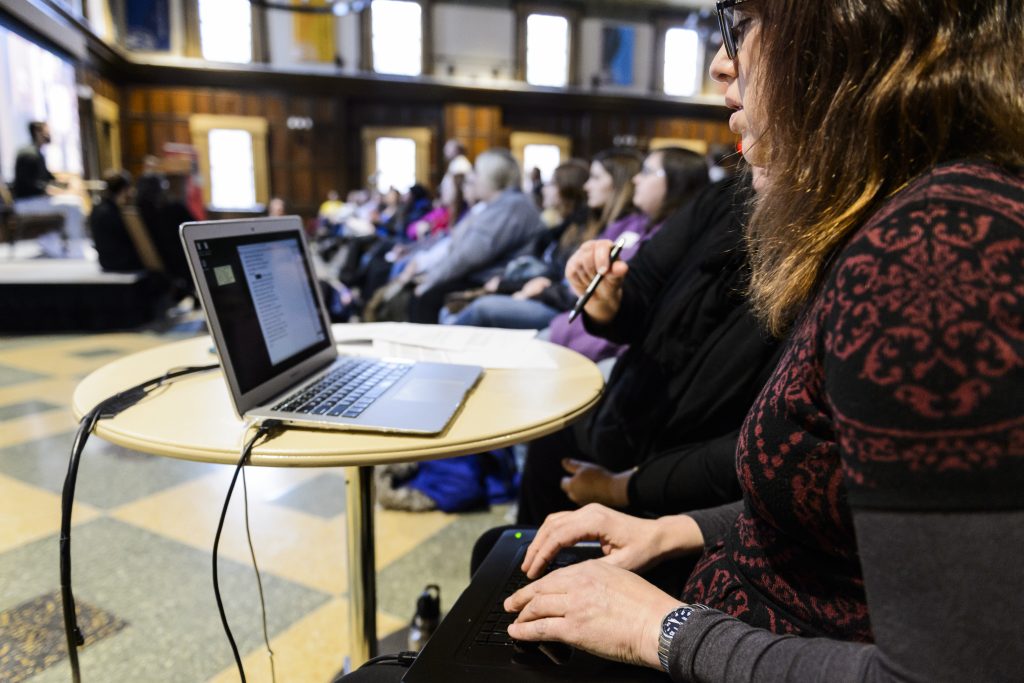 Photo of a woman typing on a steno machine, providing live, professional CART captioning services at a campus event.