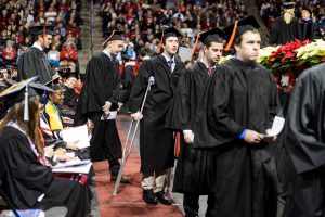 Graduate walking in a line using crutches in 2015 graduation ceremony