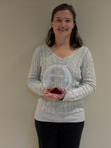 Krista Zimonick holding a Forward in Access award in front of a beige wall