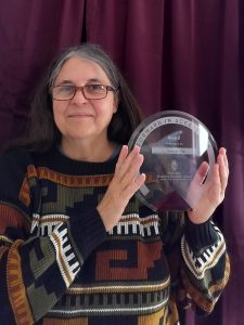 L Sherrán Pak holding a Forward in Access award in front of a maroon curtain